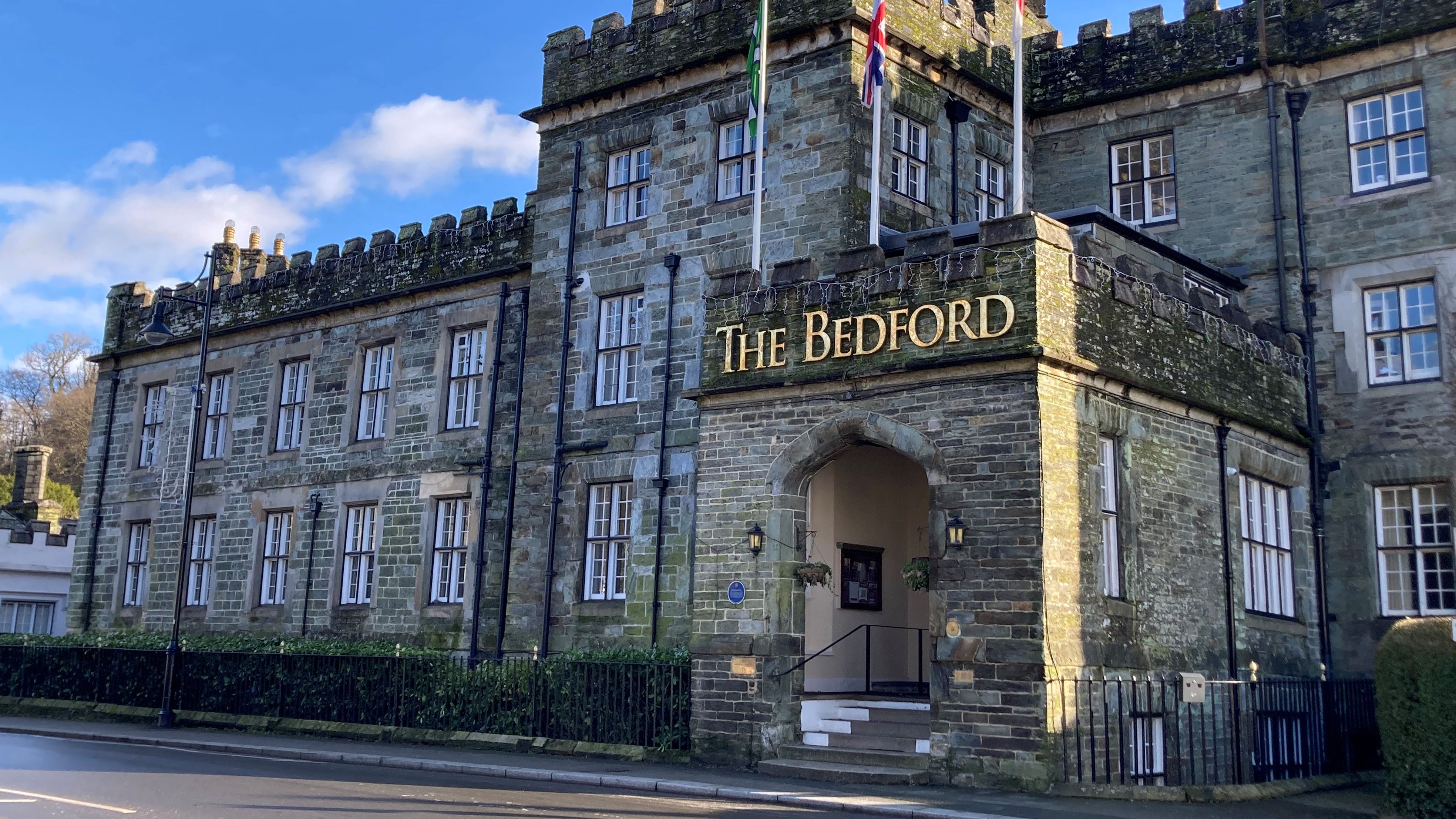 The Bedford stone building with castellated roof and flags, lit by winter sun under a blue sky