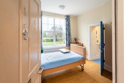 Bedroom with blue bedding and large window with view over garden