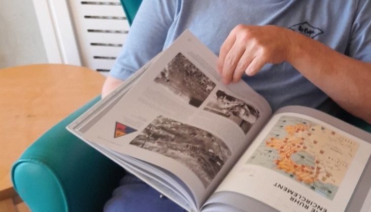 Person reading a book with photographs and maps