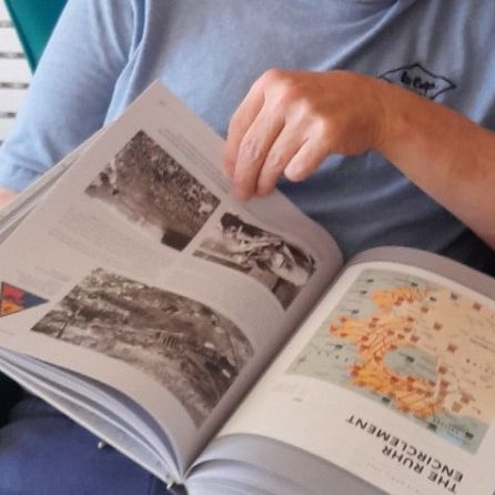 Person reading a book with photographs and maps