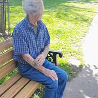 Older person sitting on a bench in a sunny park