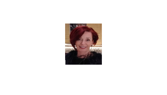 Smiling woman with short red hair wearing a black outfit