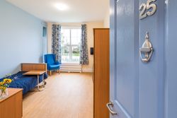 Bedroom with blue bedding and large window with view over garden