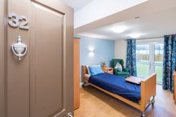Bedroom with blue bedding and large window with view over garden