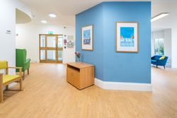 Hallway with yellow and green chairs and pictures on a blue wall