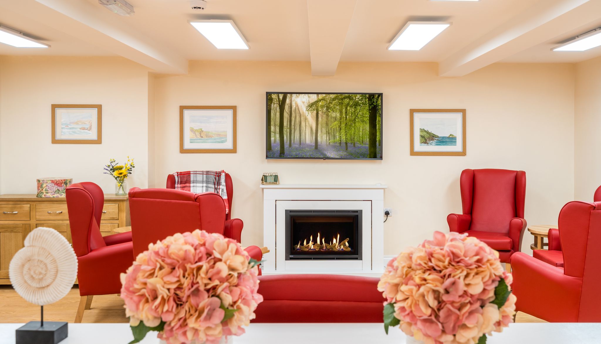 Living area with red arm chairs by fireplace