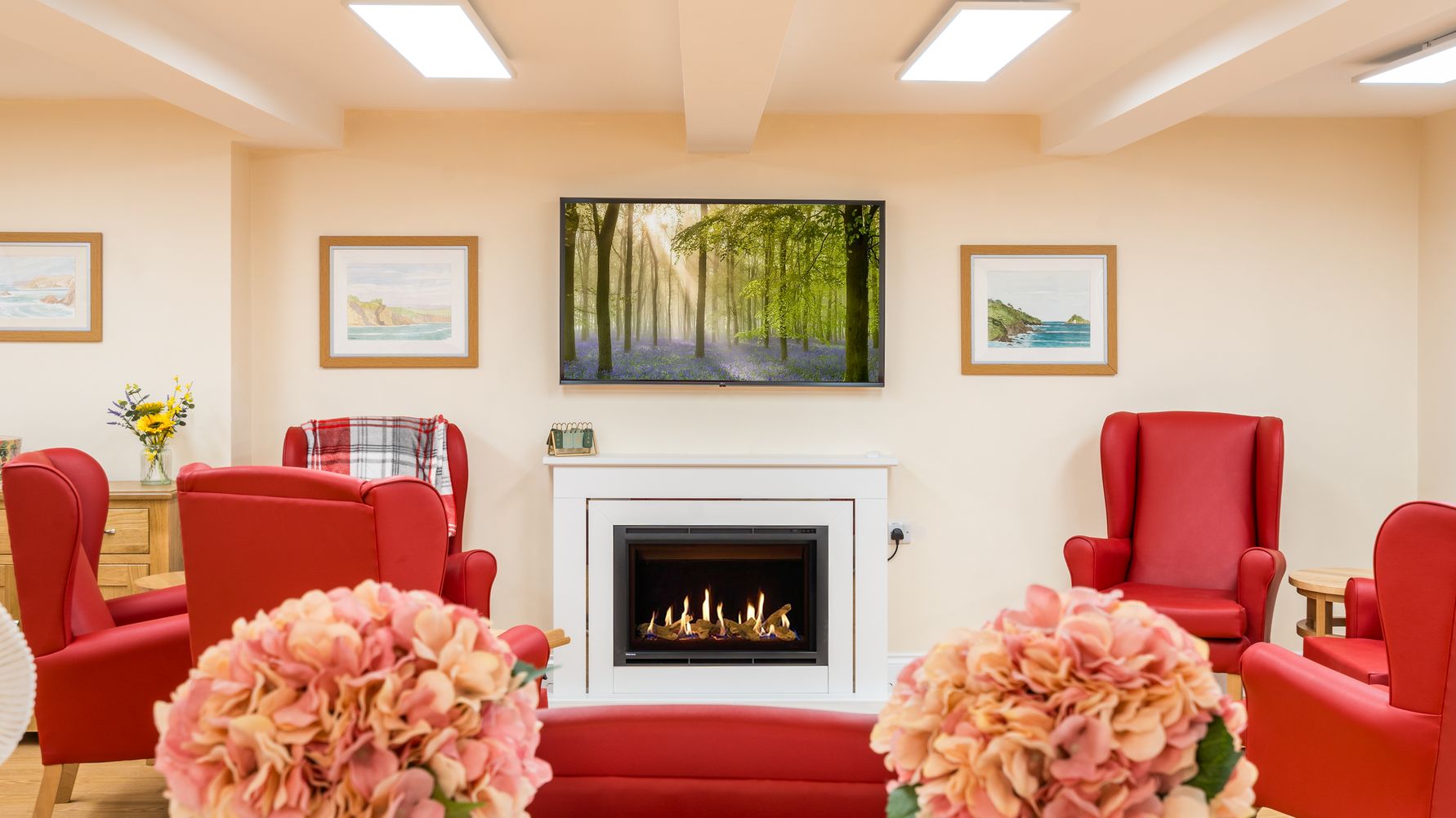 Living area with red arm chairs by fireplace