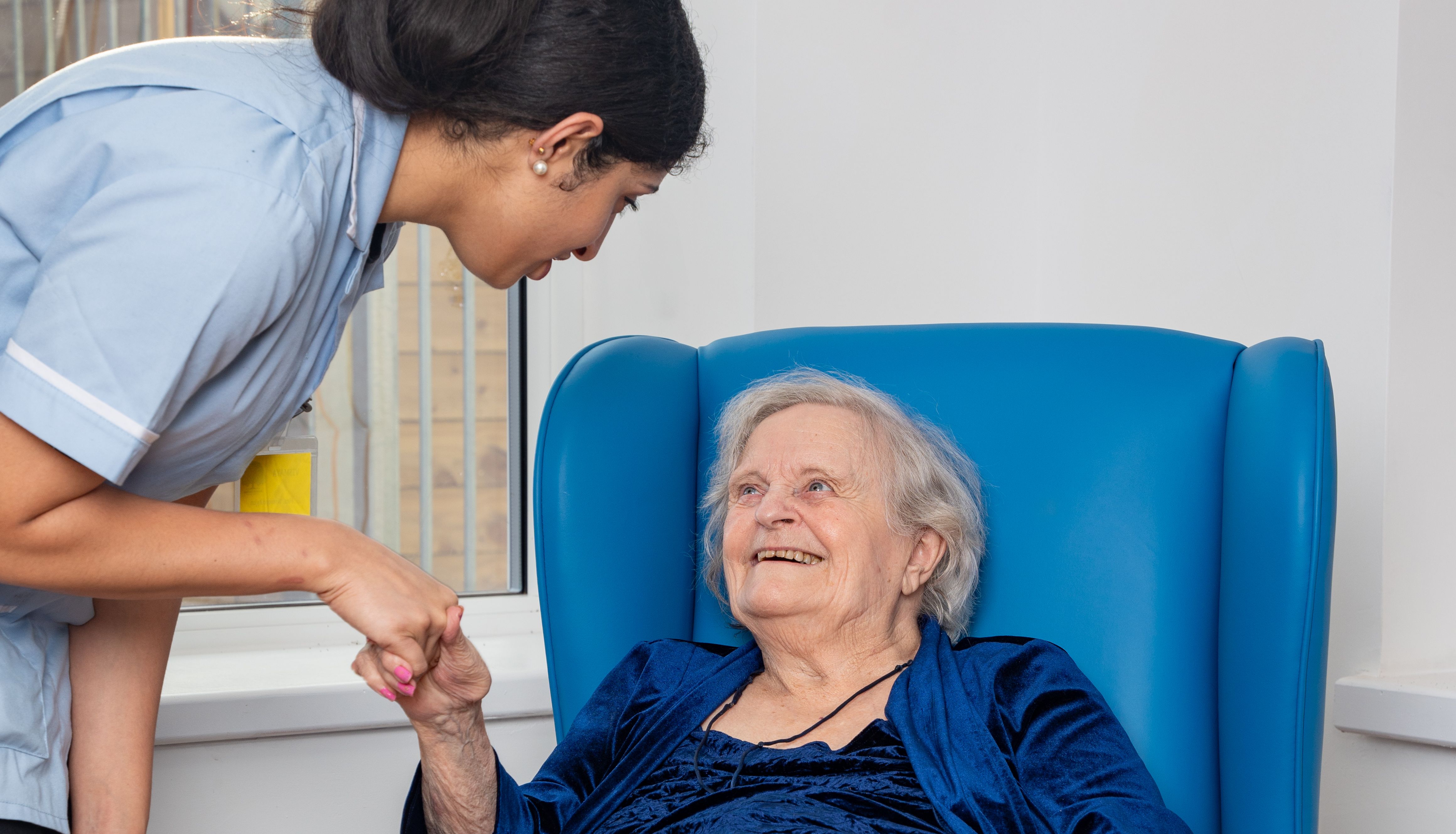Nurse warmly greeting an elderly patient