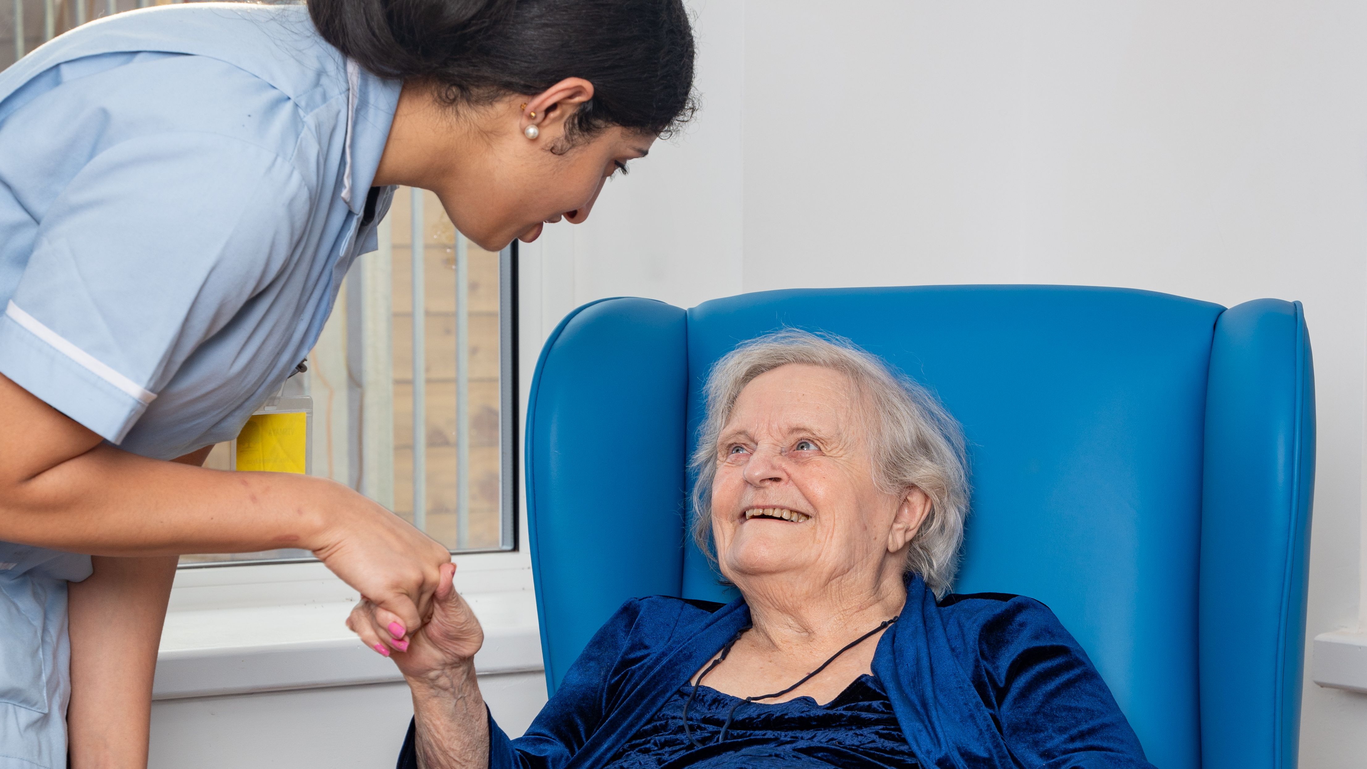 Nurse warmly greeting an elderly patient