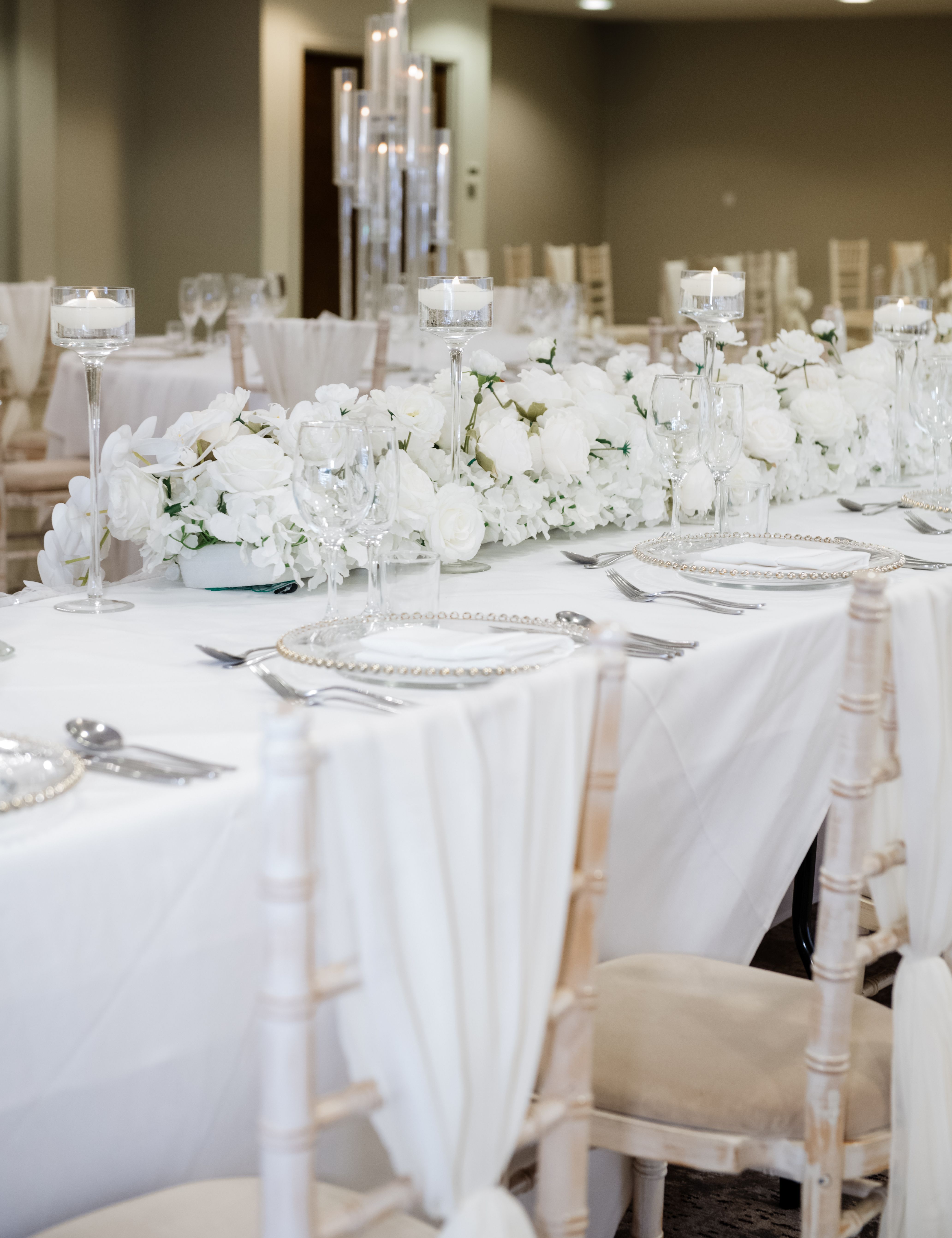 Elegant wedding or event table setting with white floral arrangements and candles