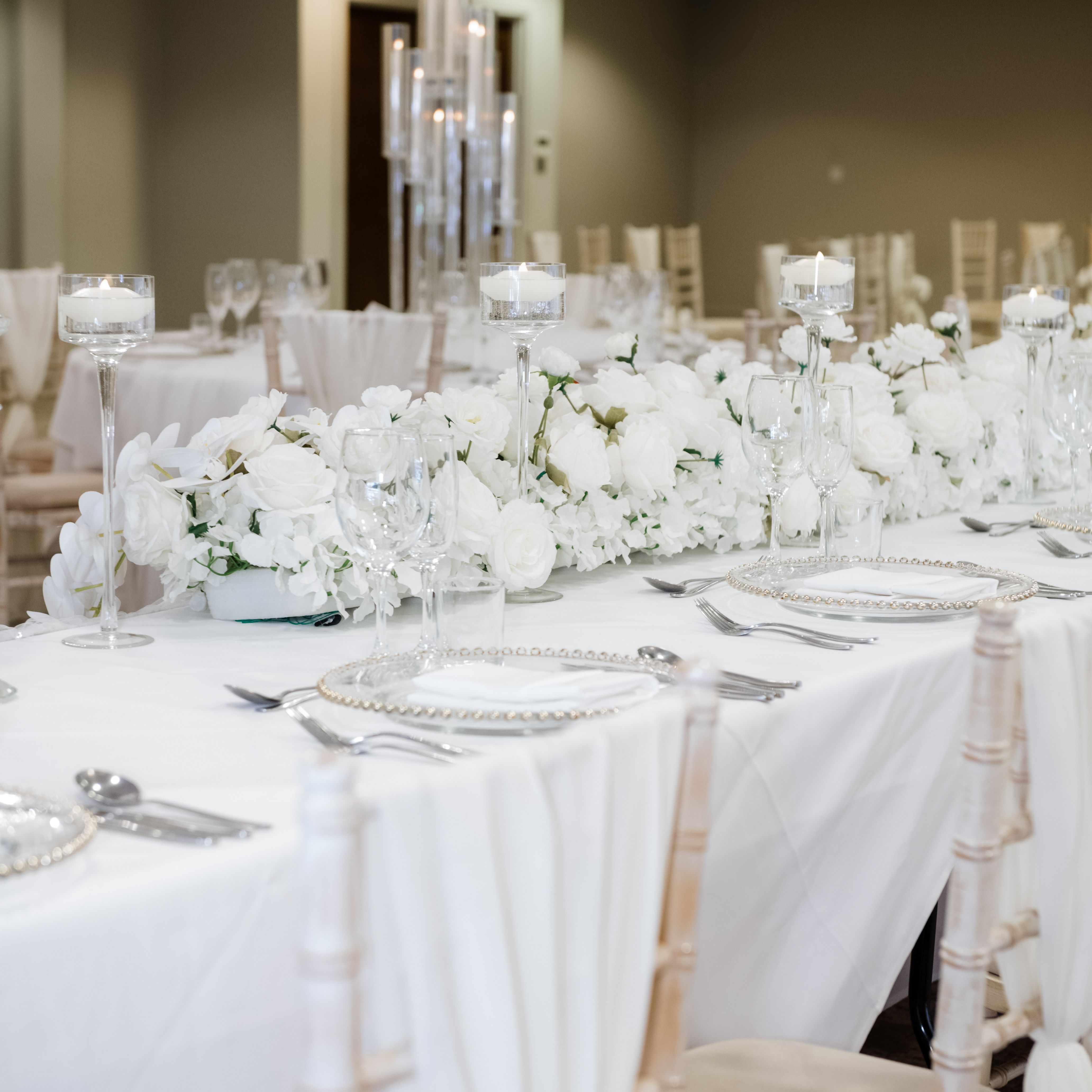 Elegant wedding or event table setting with white floral arrangements and candles