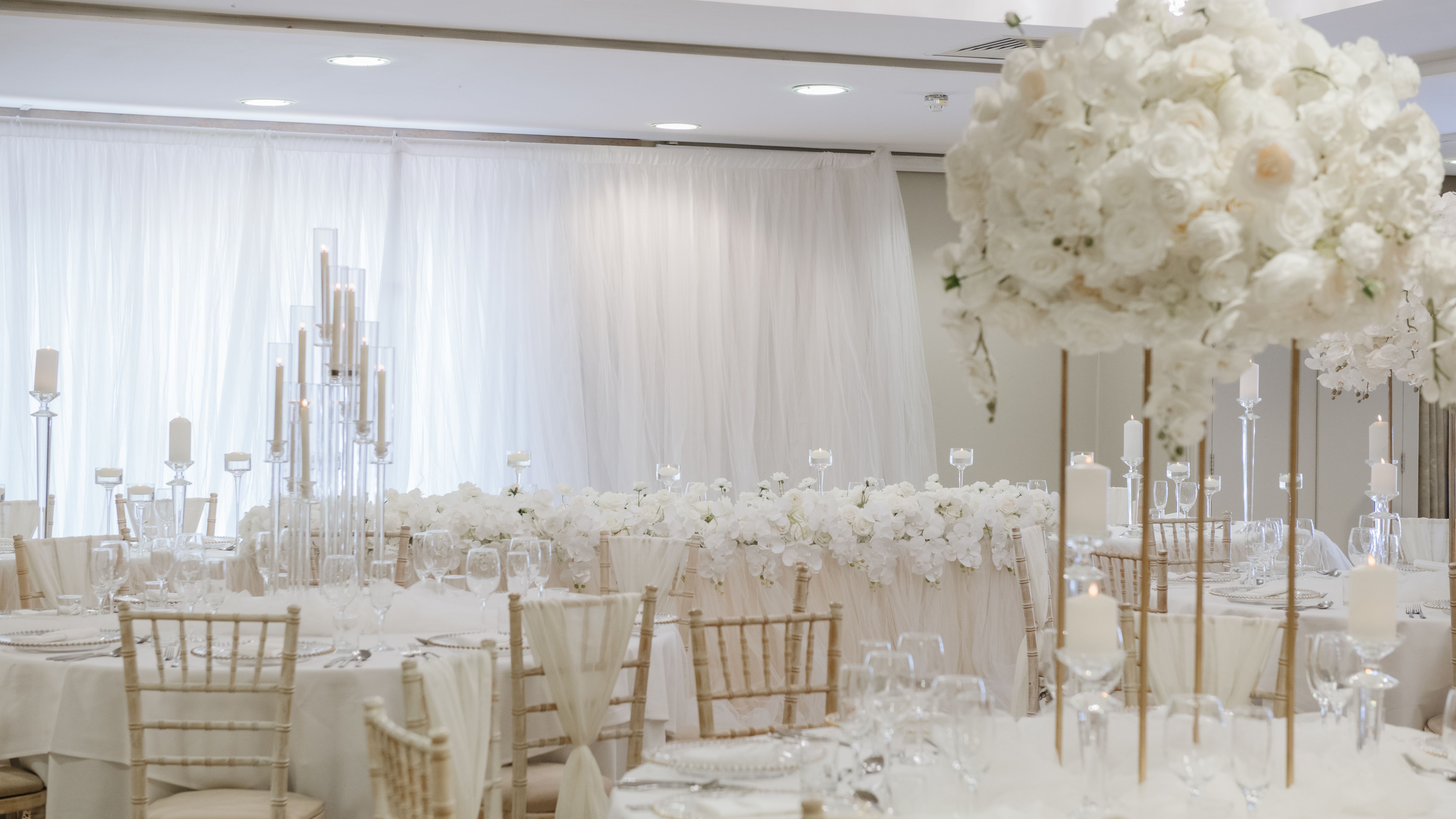 Elegant wedding reception decorated in white with floral centerpieces and candles