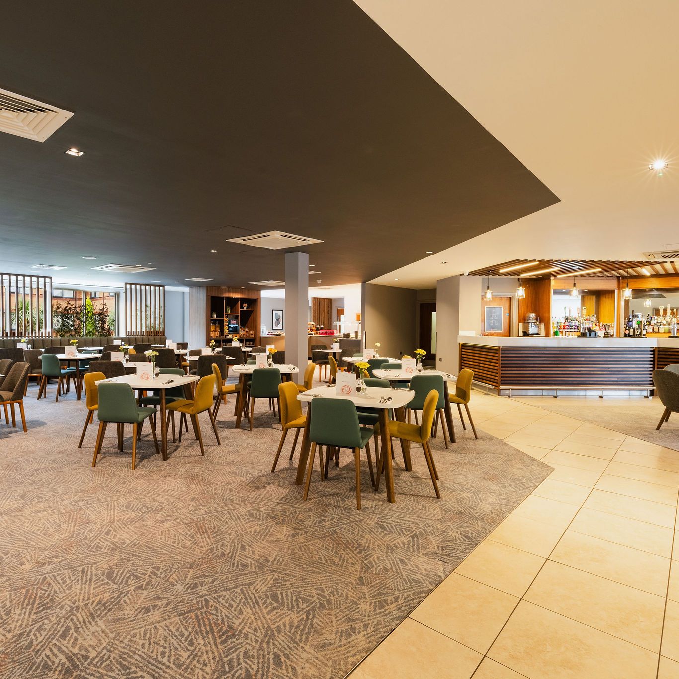 Modern hotel dining area with tables, chairs, and a bar