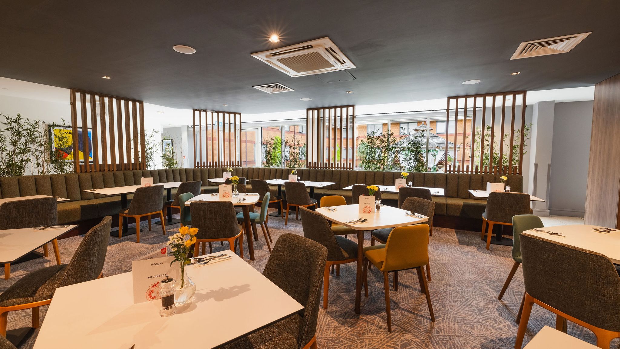 Modern hotel restaurant with neatly arranged tables and chairs, bright lighting, and large windows.