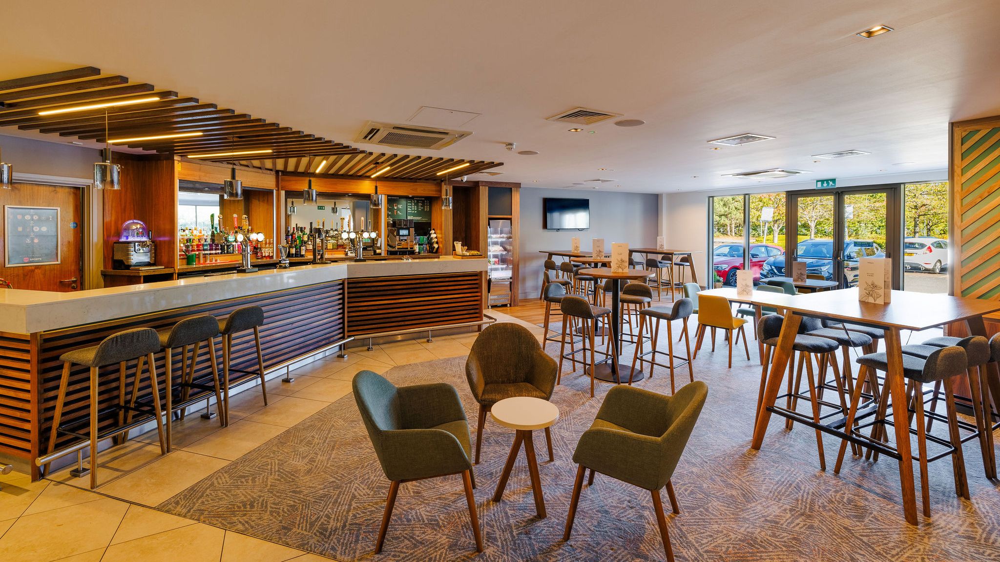 Modern hotel bar and lounge area with stylish seating and wooden decor.