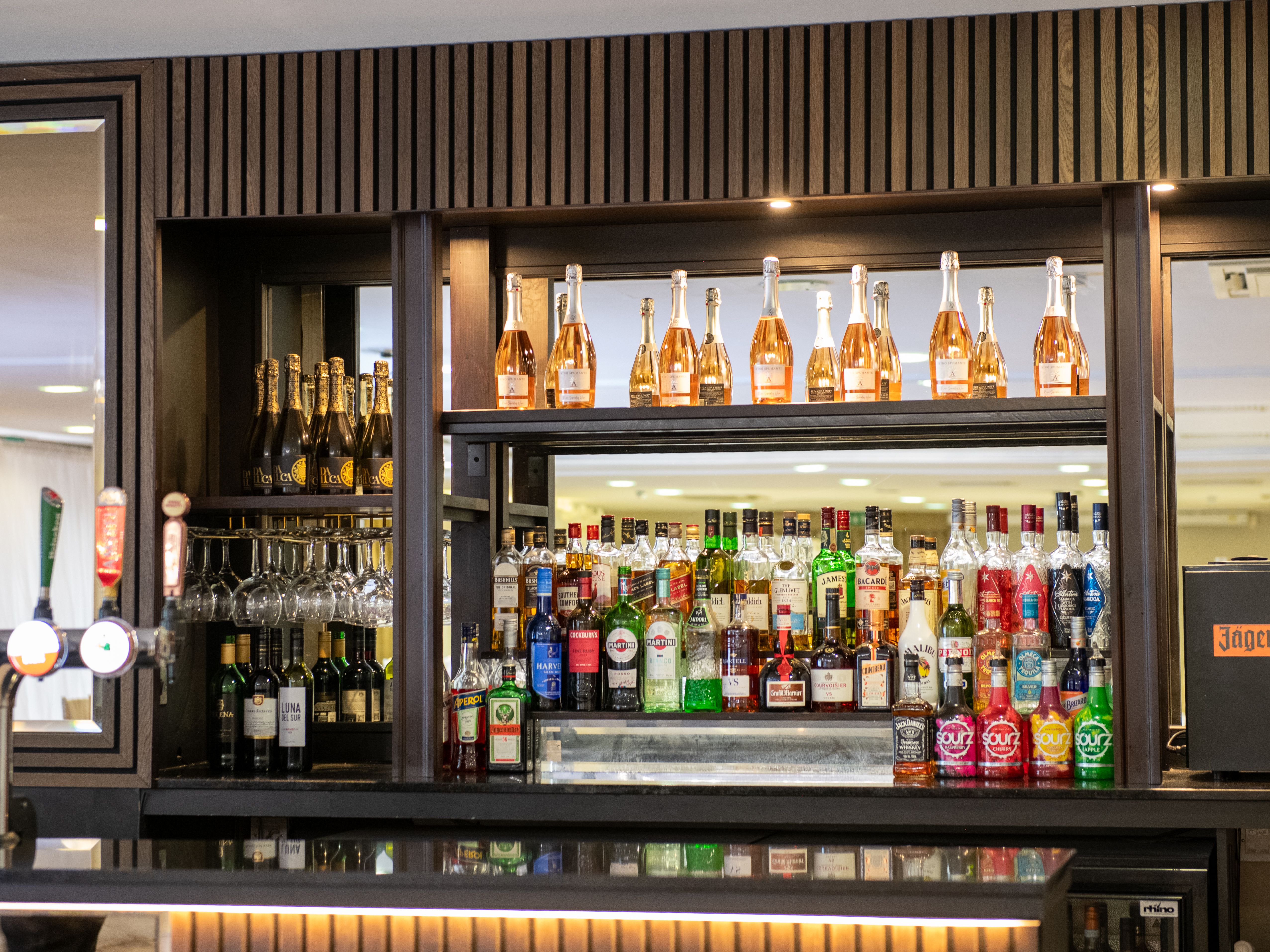 Bar shelf stocked with various bottles of liquor, wine, and glasses.