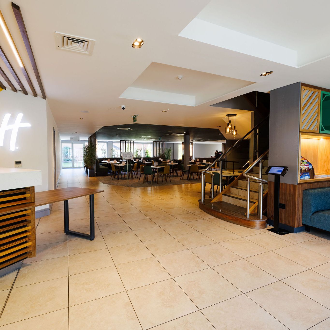 Modern hotel lobby with seating area, staircase, and reception desk.
