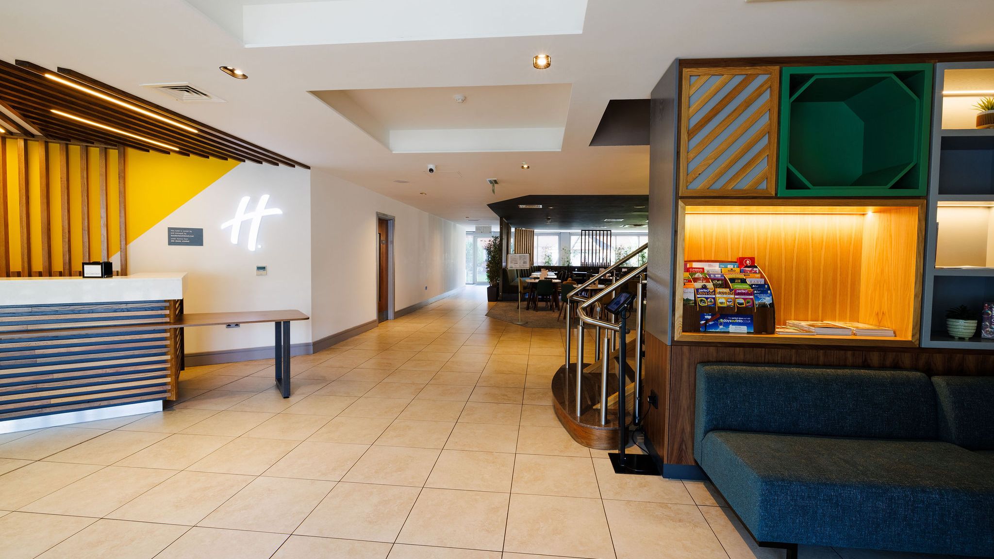 Modern hotel lobby with reception desk, seating area, and brochure display.
