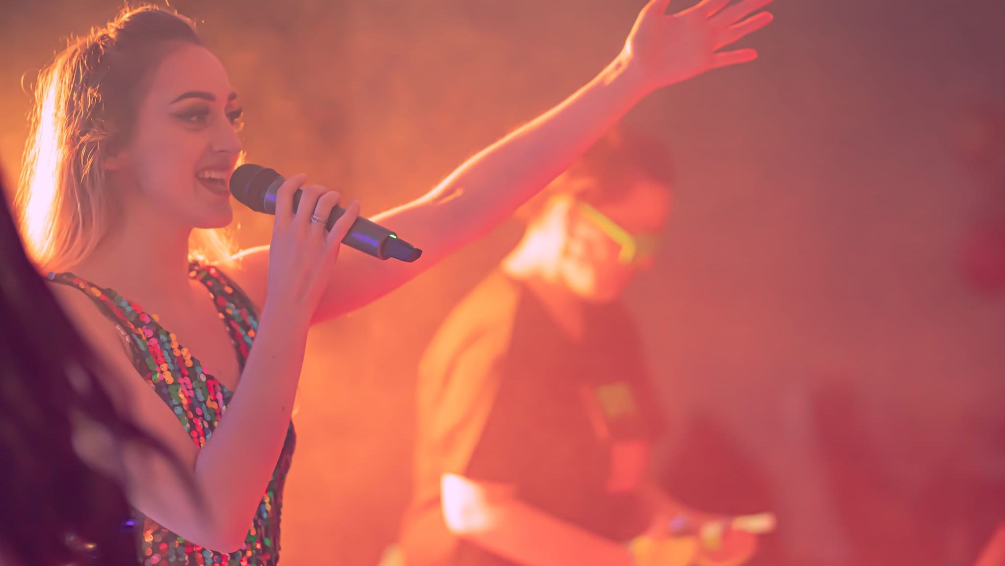Woman singing on stage with microphone in colorful lighting