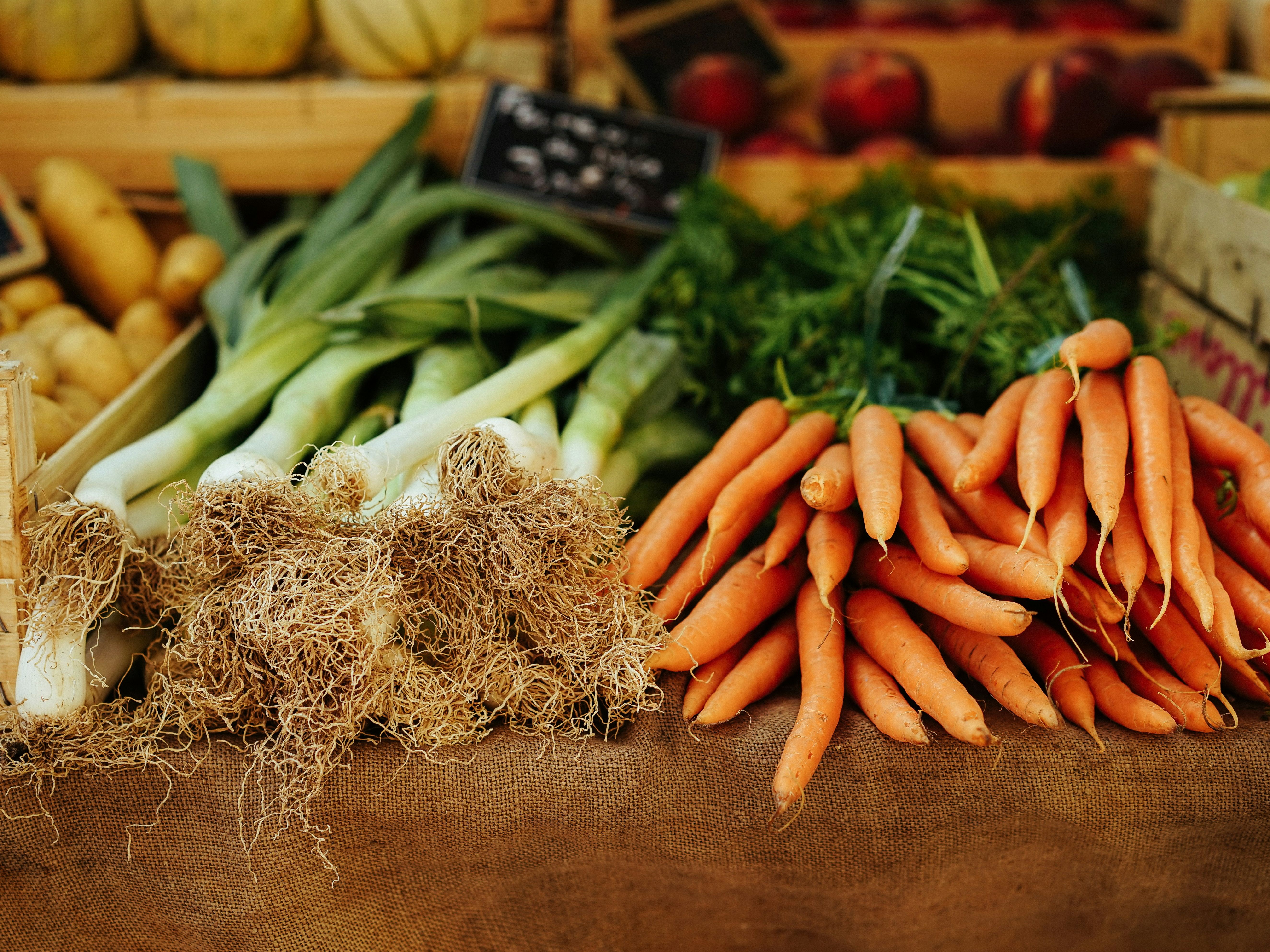 Fresh carrots and leeks on display at a market stand