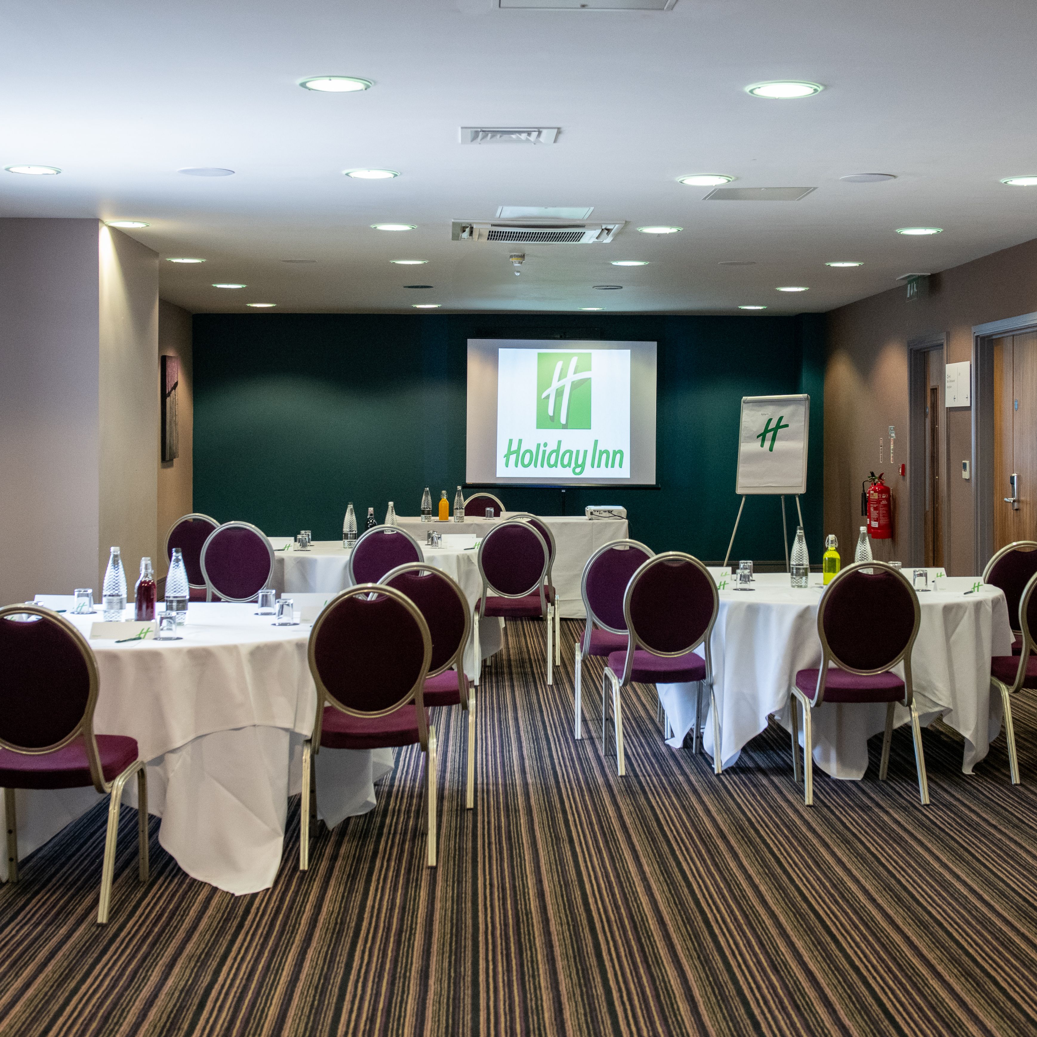 Holiday Inn conference room with round tables, chairs, and a presentation screen