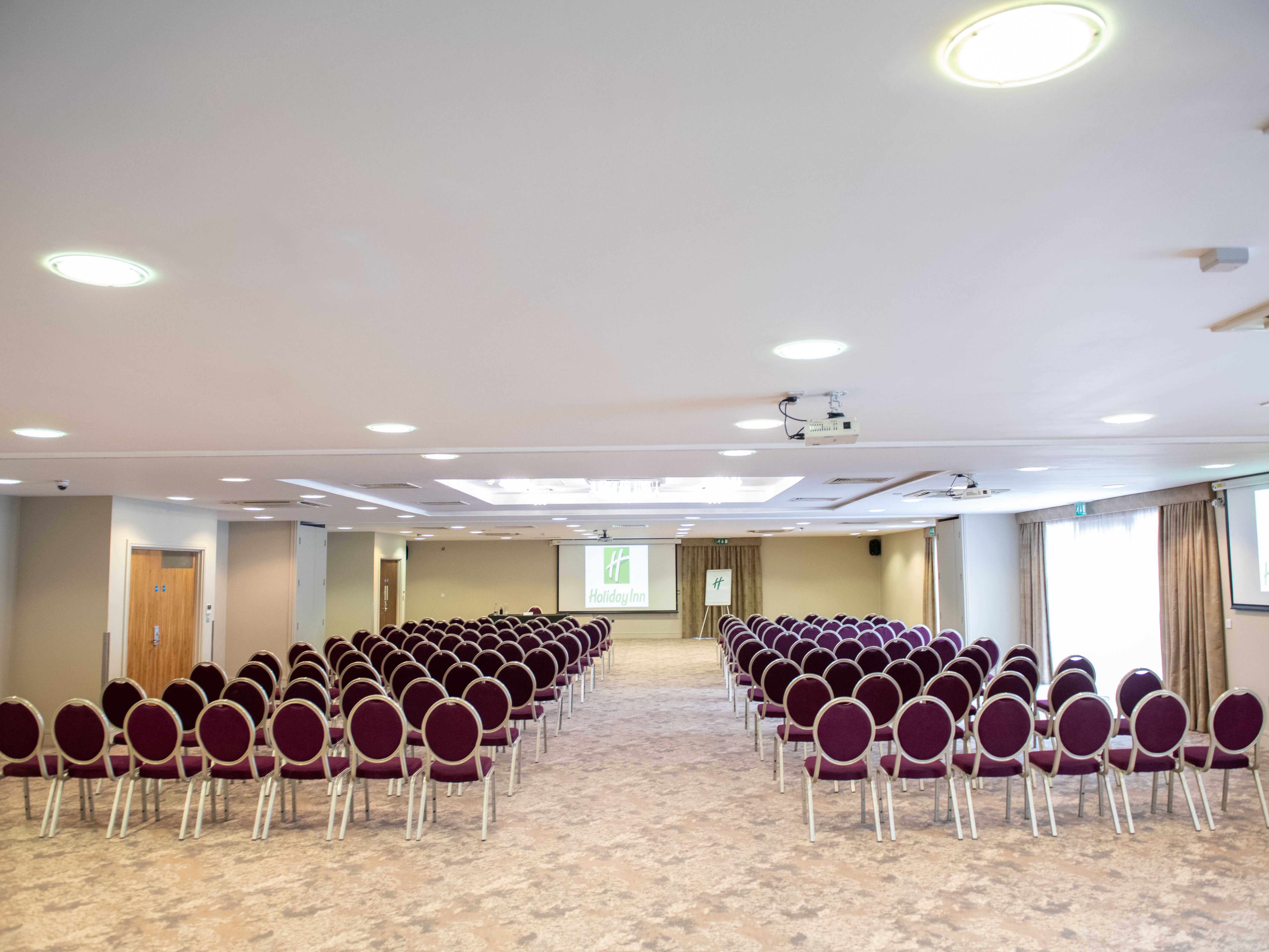 Conference room with rows of chairs facing a screen displaying the Holiday Inn logo