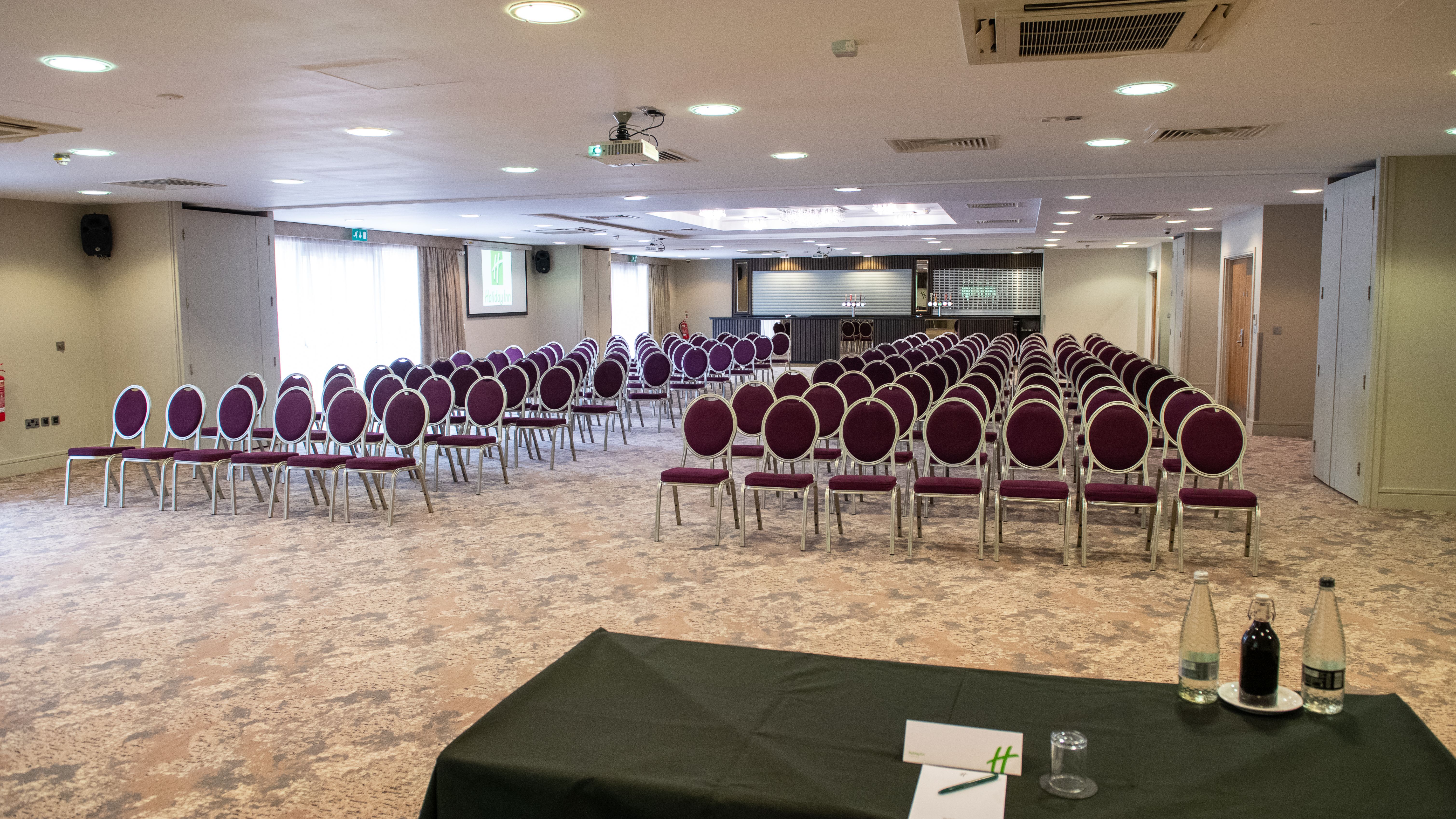 Conference room with rows of empty chairs and a table at the front.
