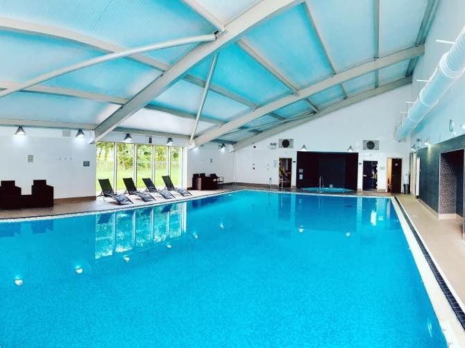 Indoor swimming pool with lounge chairs and modern ceiling