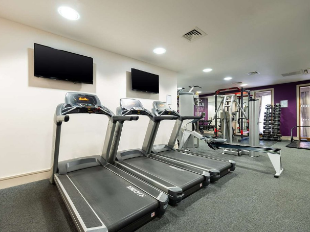 Modern gym with treadmills, weight machines, and TVs on the wall