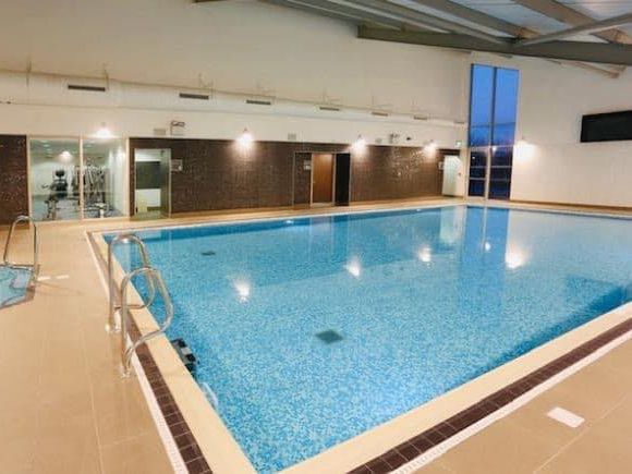 Indoor swimming pool with clear blue water and poolside steps