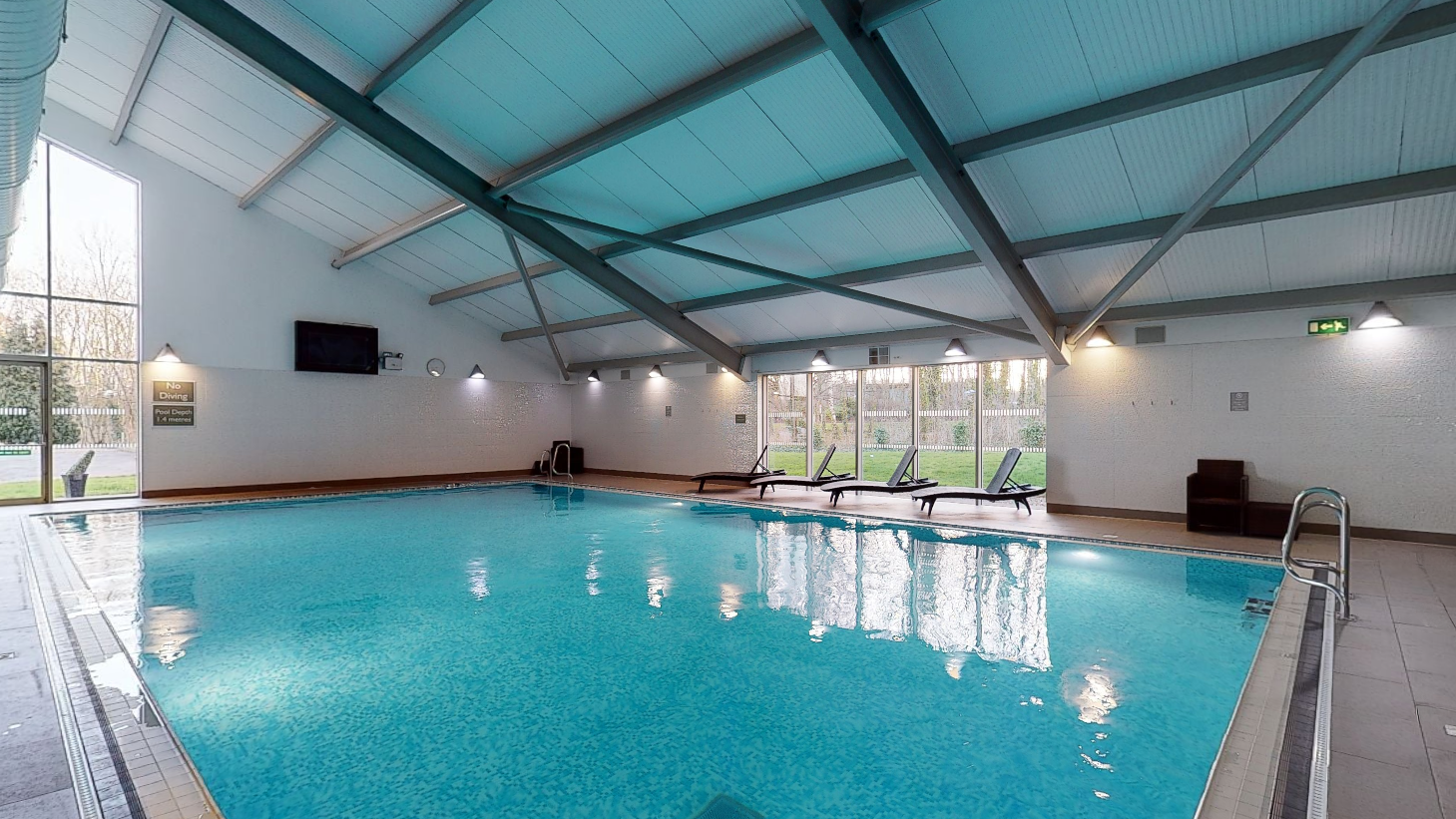Indoor swimming pool with lounge chairs and large windows
