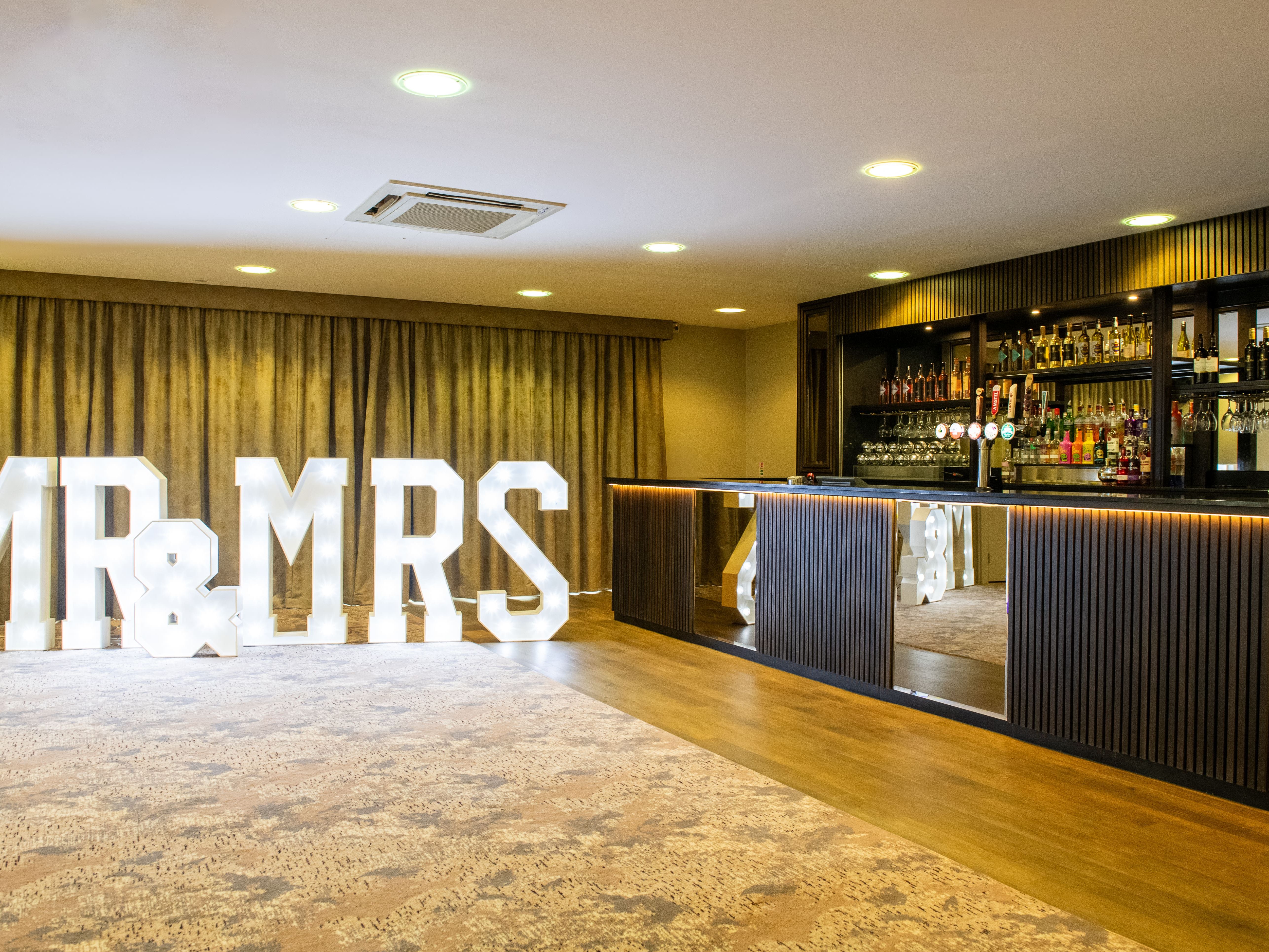 Lit 'MR & MRS' sign next to a bar at an event venue