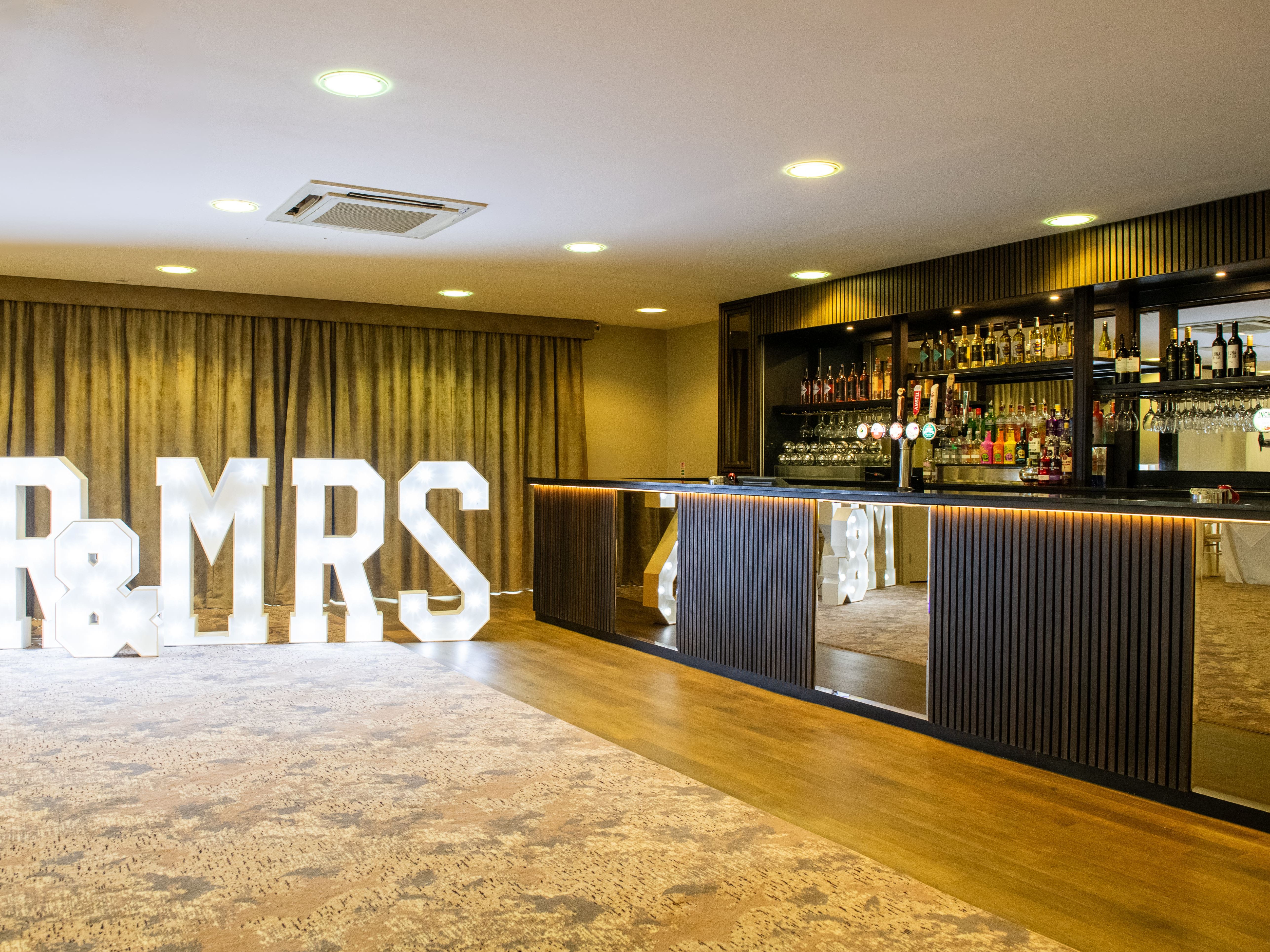 Lit 'MR & MRS' sign next to a bar at an event venue
