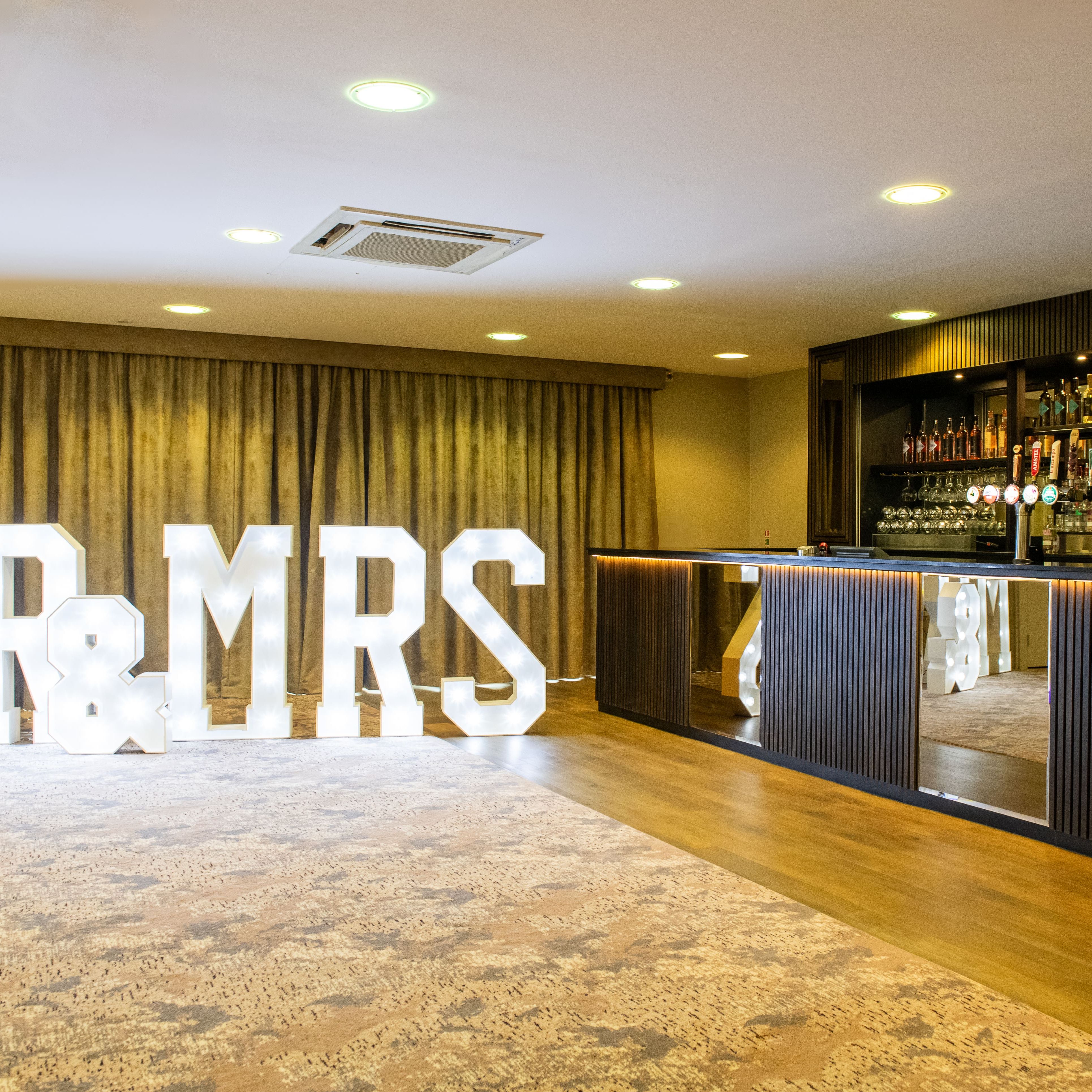 Lit 'MR & MRS' sign next to a bar at an event venue