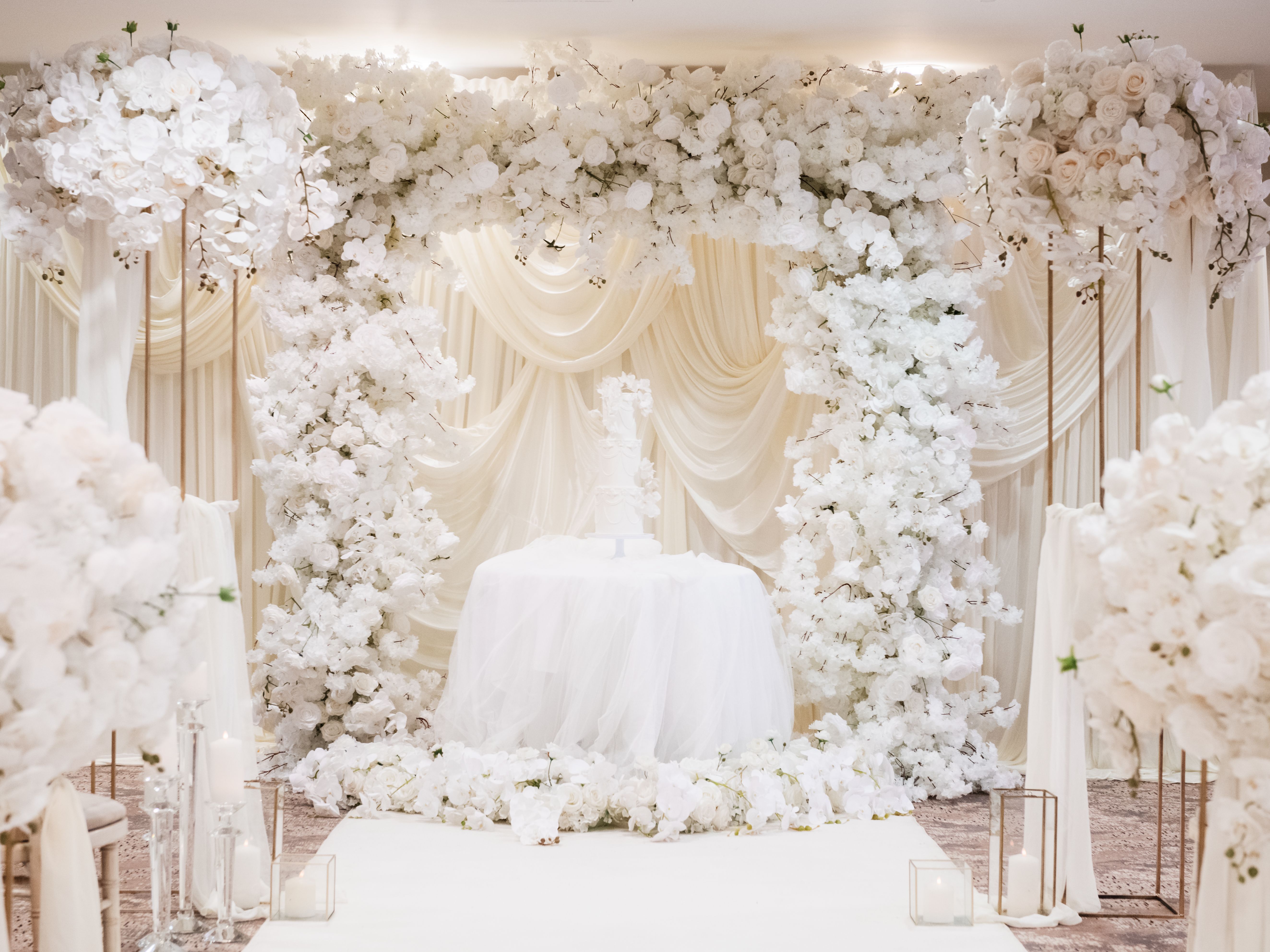 Elegant wedding ceremony setup with white floral arch and draped fabric.