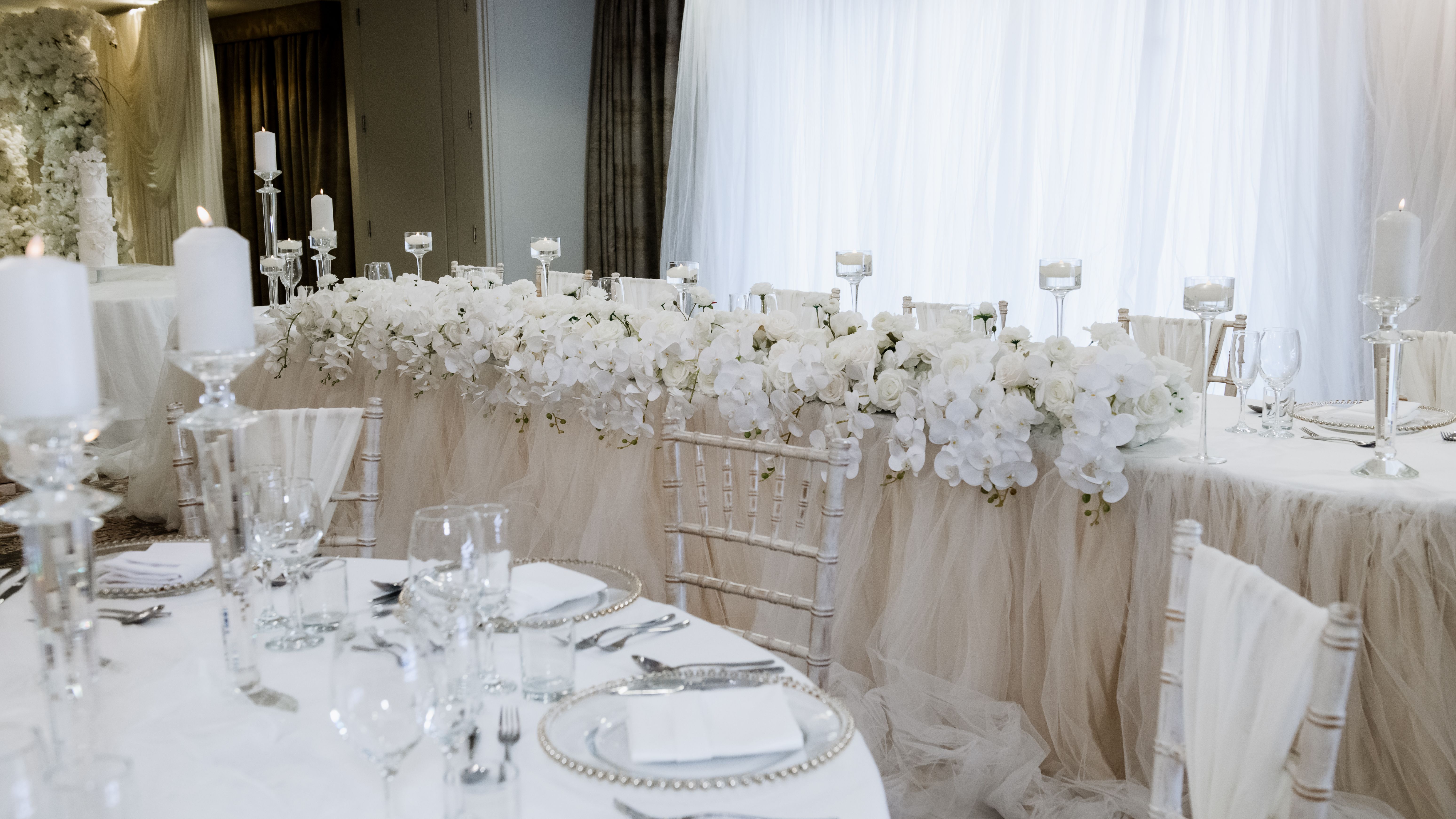 Elegant wedding reception table setting with white flowers and candles.