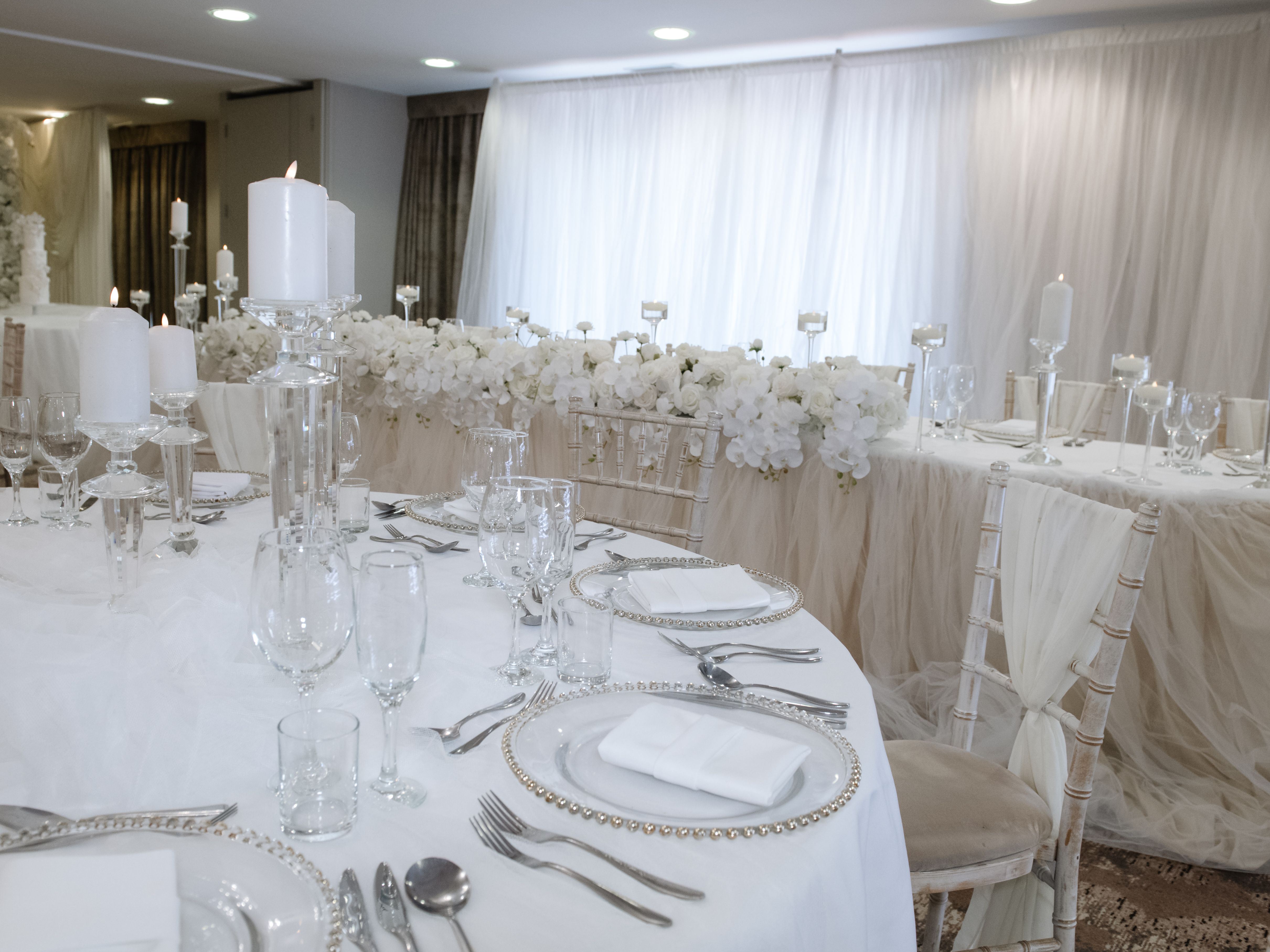 Elegant wedding table setup with white and silver decor and candles.