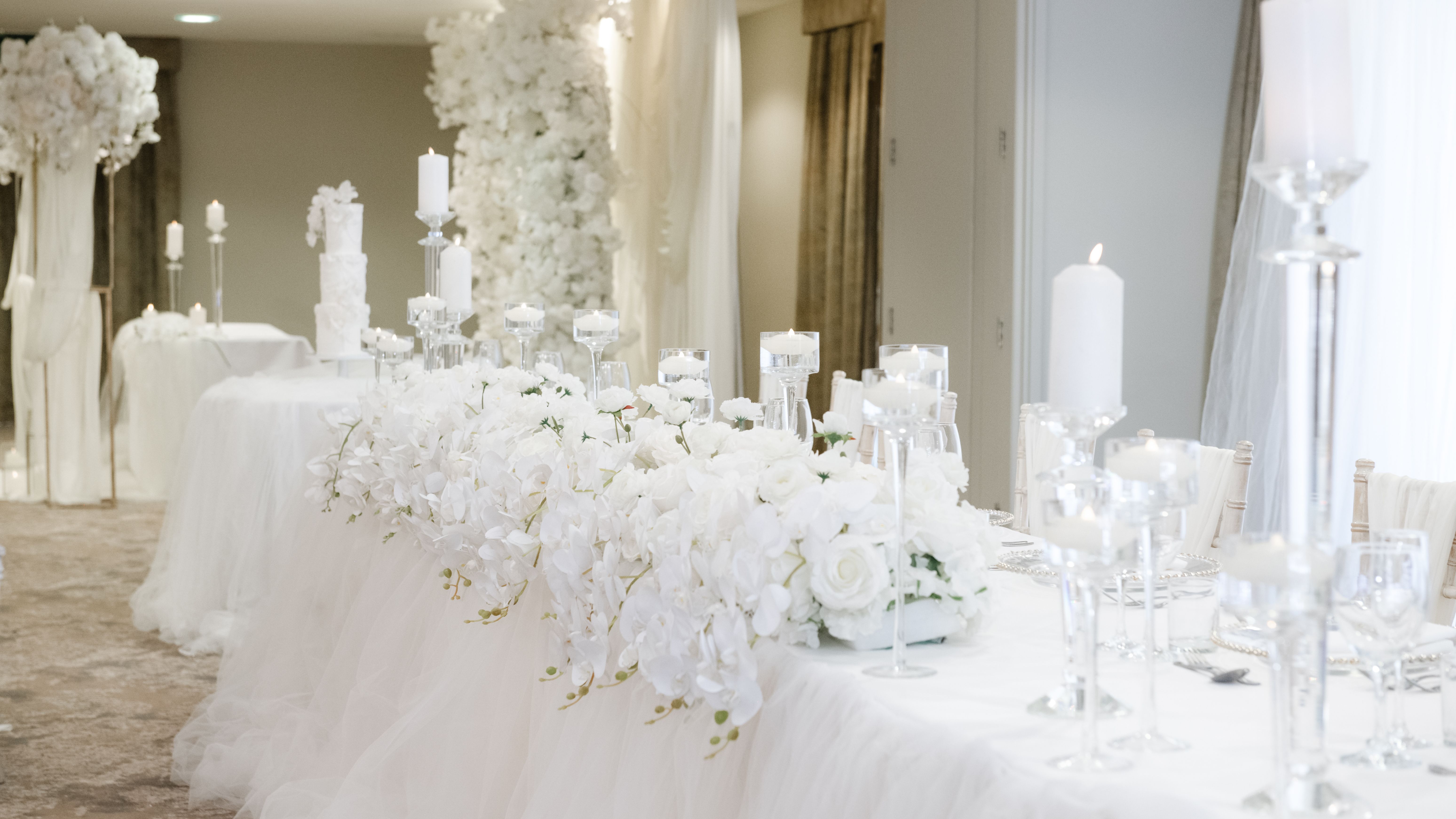 Elegant wedding reception table decorated with white flowers and candles