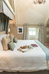 Bright and cozy bedroom with a tray of breakfast on the bed and magazines, featuring soft pillows and elegant decor.