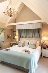 Elegant bedroom with king-size bed, canopy, chandelier, and breakfast tray.