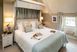 Elegant bedroom with a large bed, soft lighting, and breakfast tray