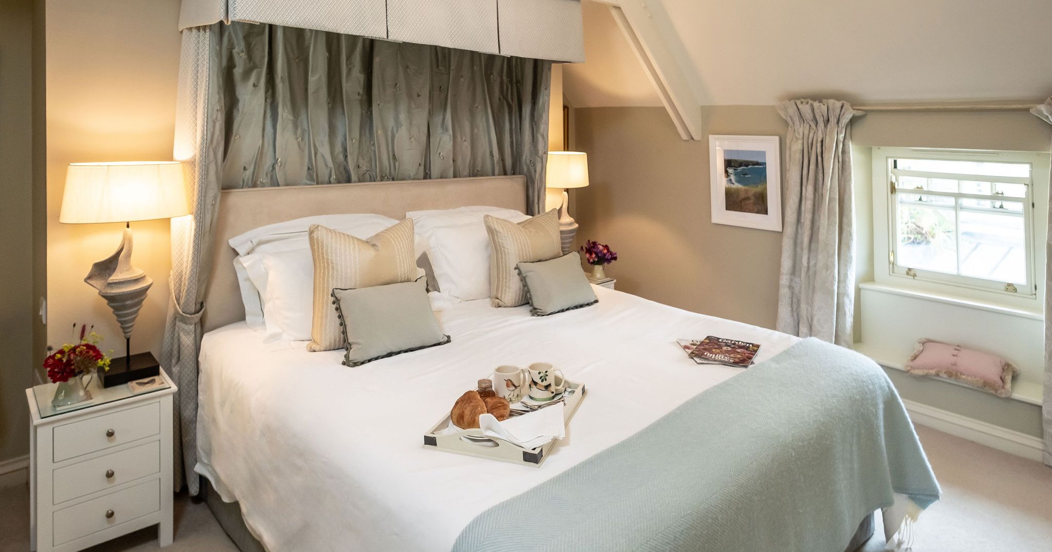 Elegant bedroom with a large bed, soft lighting, and breakfast tray