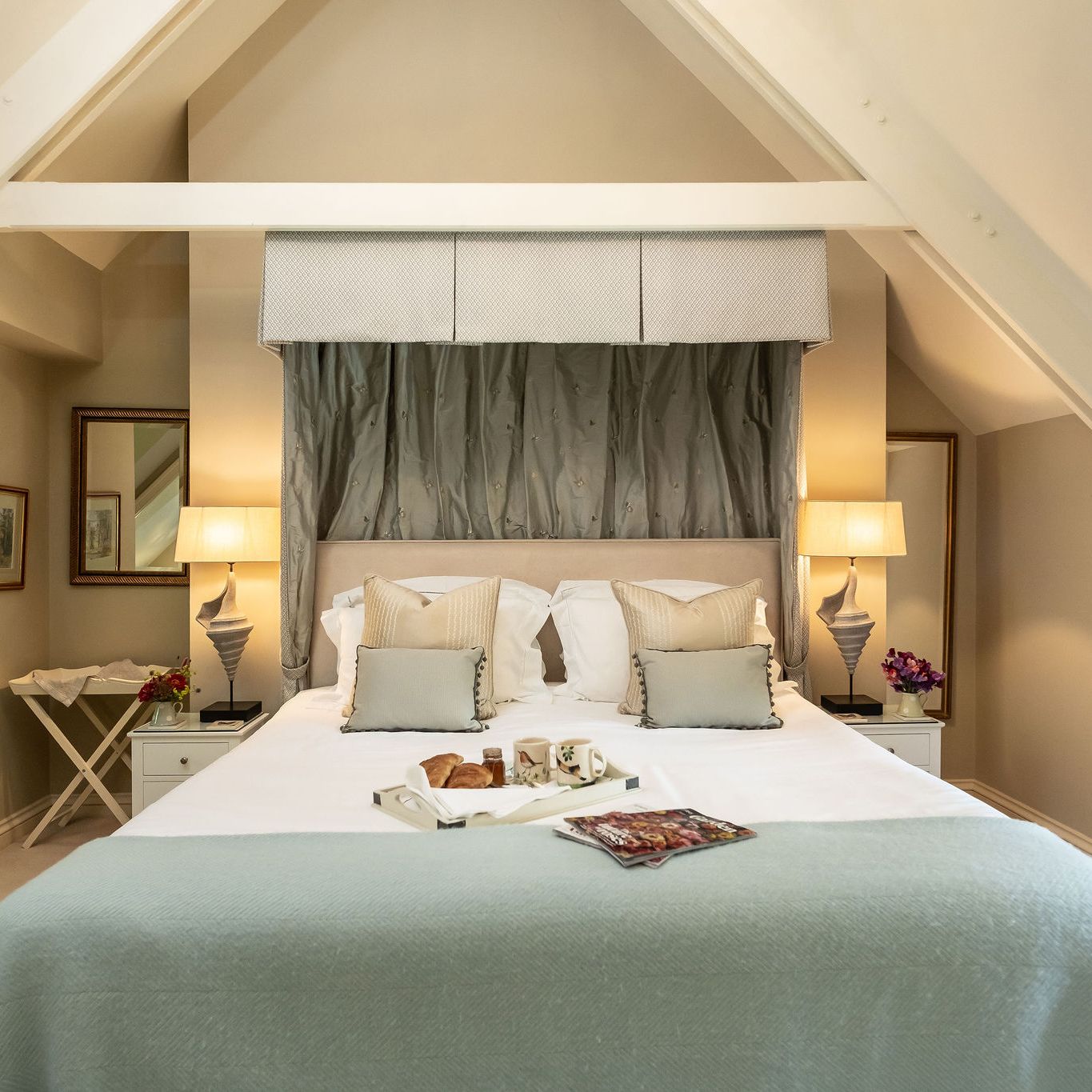 Cozy and elegant bedroom with a large bed, decorative pillows, bedside lamps, and breakfast tray