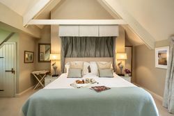 Cozy and elegant bedroom with a large bed, decorative pillows, bedside lamps, and breakfast tray
