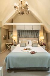 Elegant bedroom with a neatly made bed, a chandelier, bedside tables with lamps, and a tray with breakfast items.