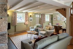Cozy, stylish living room and dining area with pastel green walls, comfortable seating, and rustic wooden accents