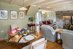 Cozy cottage living and dining area with stone fireplace and comfortable seating