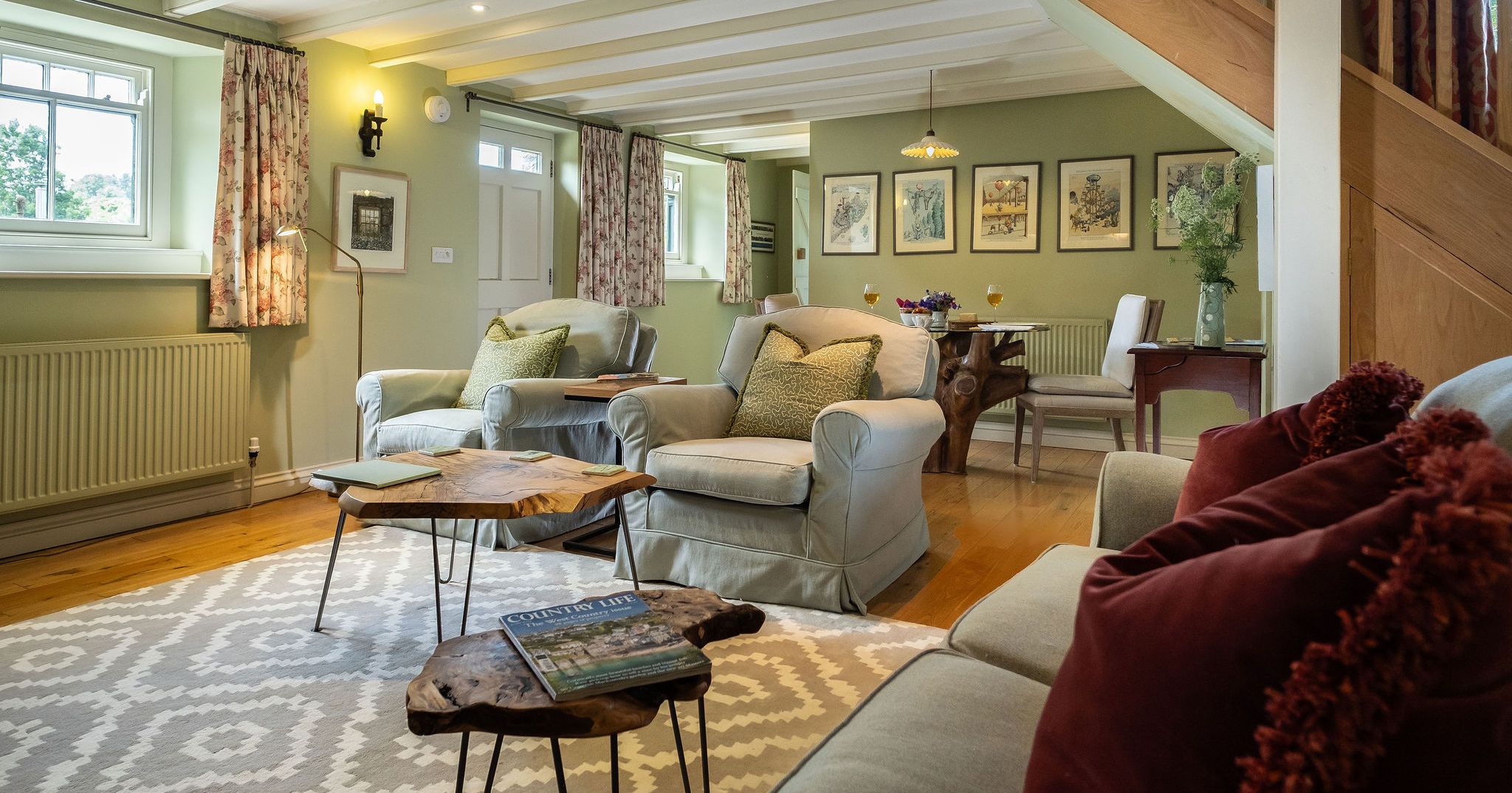 Cozy living and dining area with armchairs, sofa, wooden tables, and decorative accents