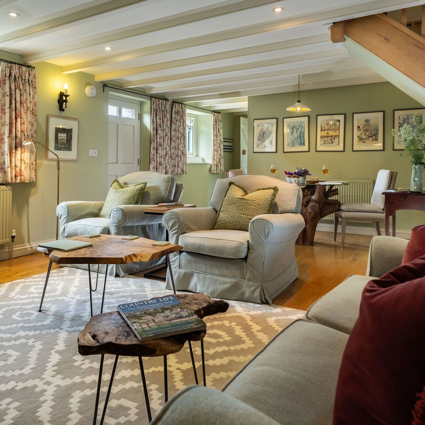 Cozy living and dining area with armchairs, sofa, wooden tables, and decorative accents