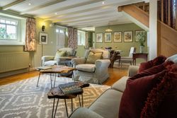 Cozy living and dining area with armchairs, sofa, wooden tables, and decorative accents